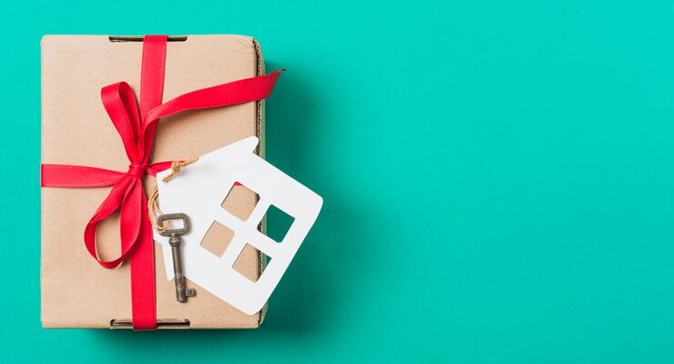 brown-gift-box-tied-with-red-ribbon-house-key-turquoise-surface_23-2148102754